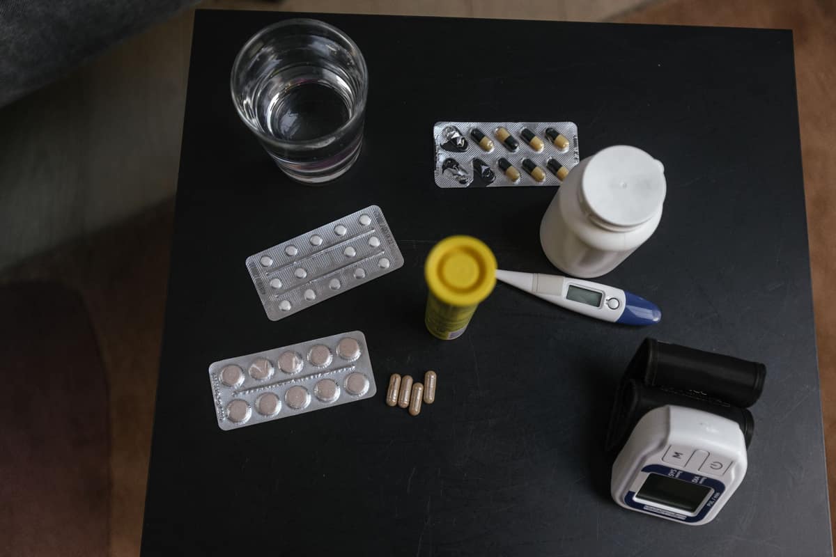 Medication packets and a glass of water on a table