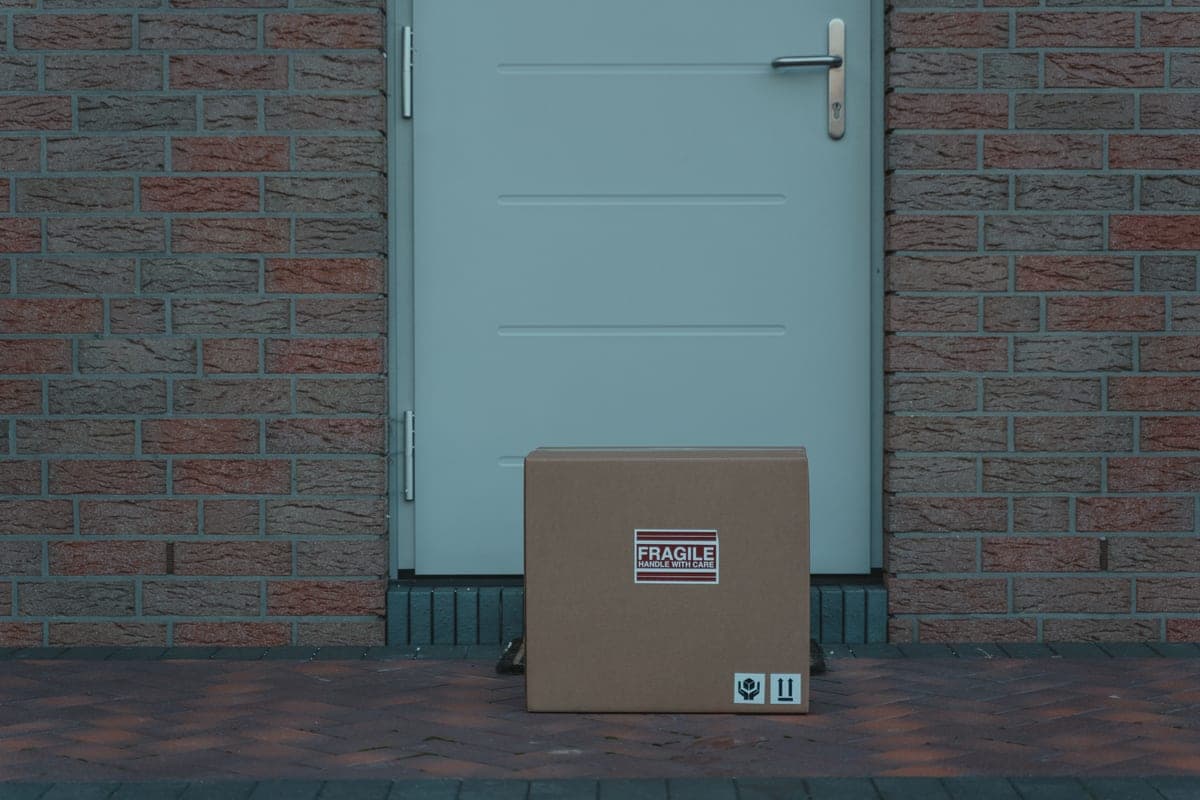 A cardboard delivery package waiting on a doorstep in daylight