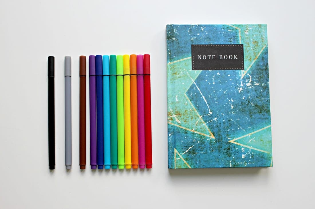 Fresh notebooks, pens and school supplies laid out on a bright desk