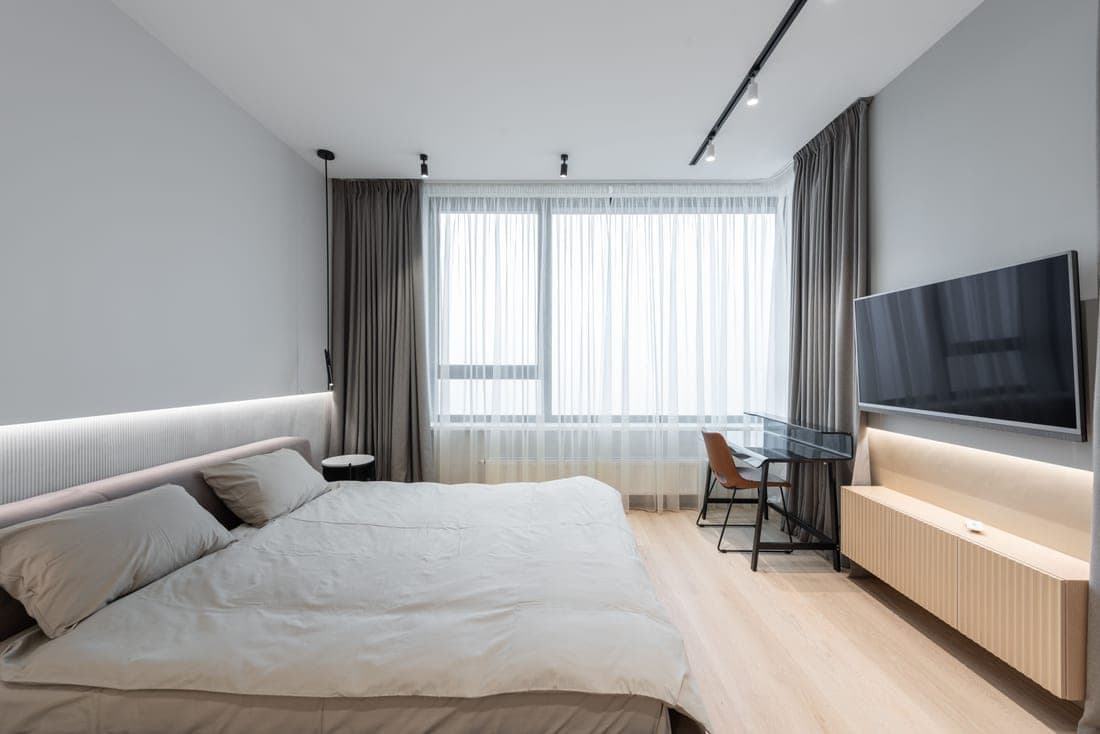 A bright, minimally furnished dorm bedroom with a bed and desk