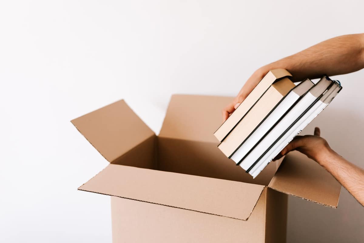 A person packing books into a cardboard box