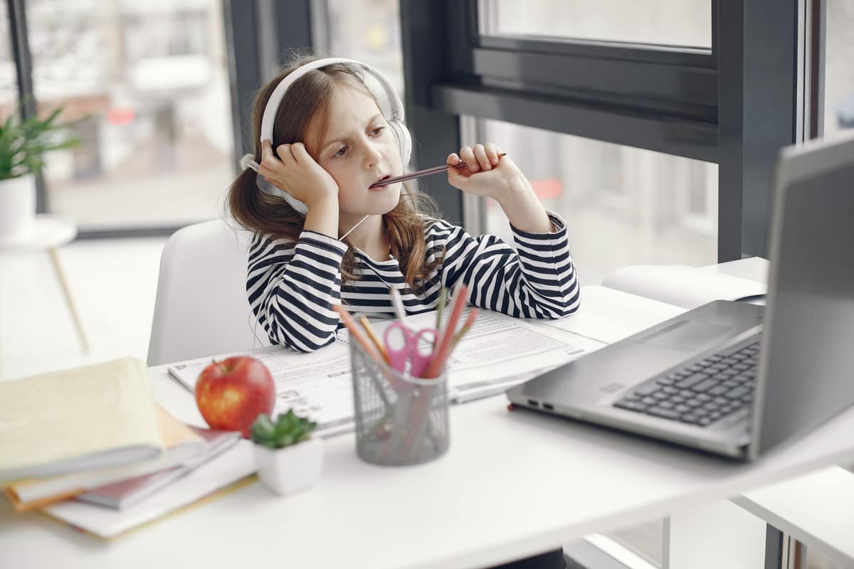 A laptop, headphones and notebook on a bright study desk
