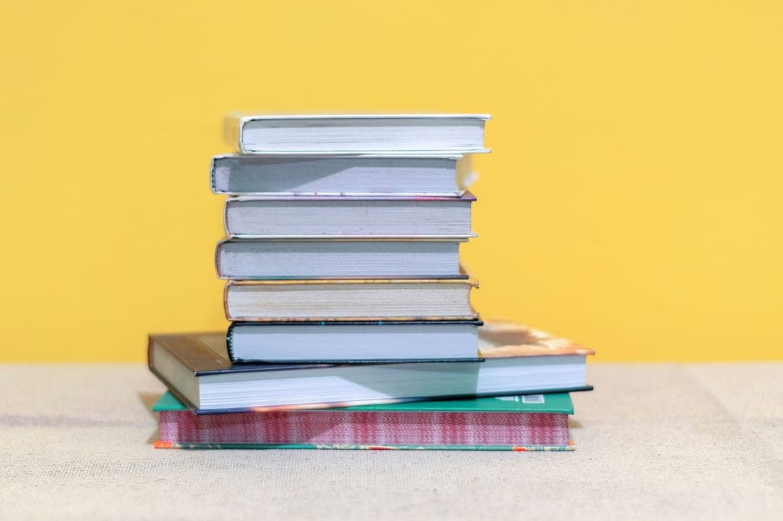 A stack of textbooks on a desk in natural daylight