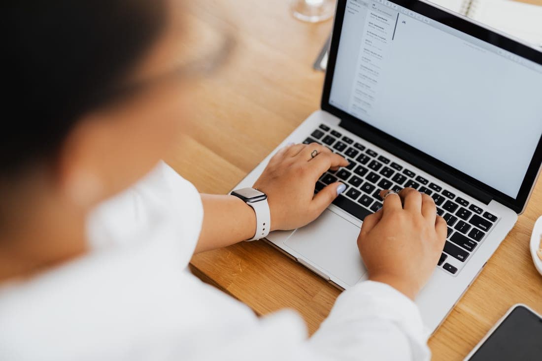 Someone typing an email on a laptop at a bright desk