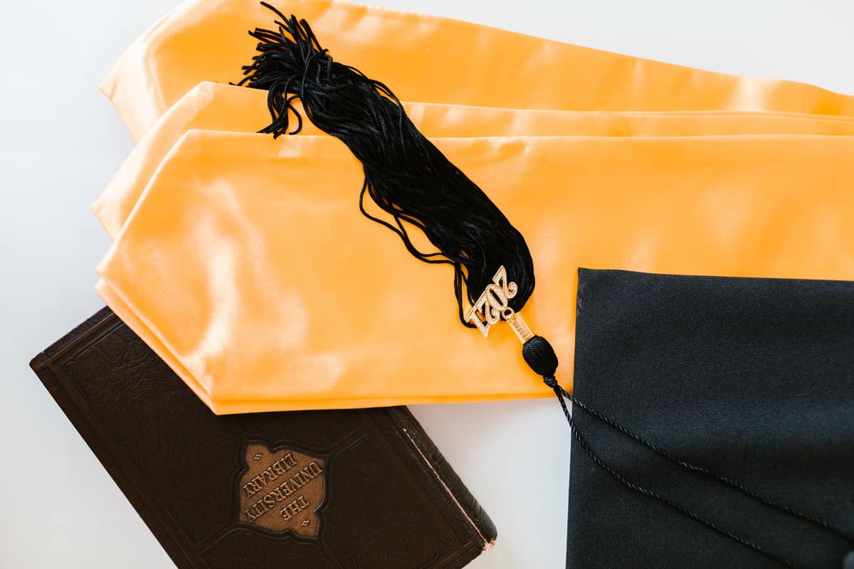 A graduation cap resting on books in bright daylight