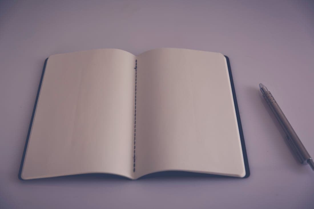 An open notebook and pen on a bright, uncluttered desk