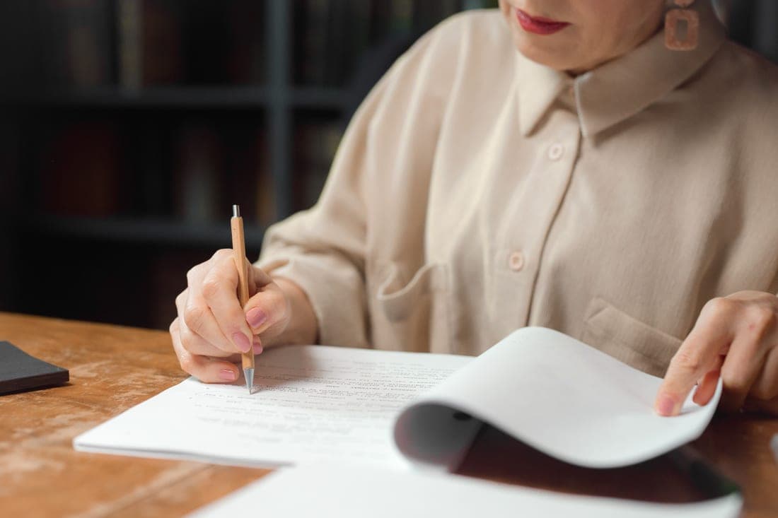 Printed pages being marked up with a pen at a bright desk