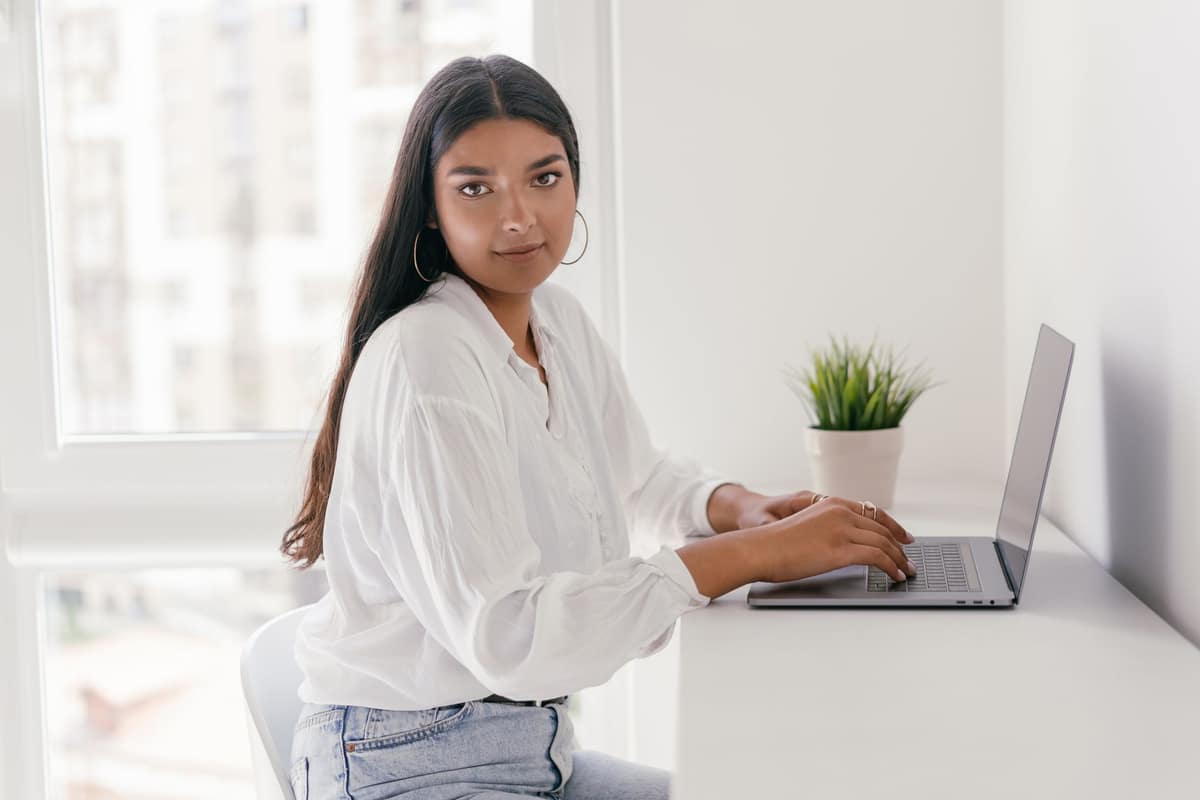 A student typing on a laptop at a bright desk