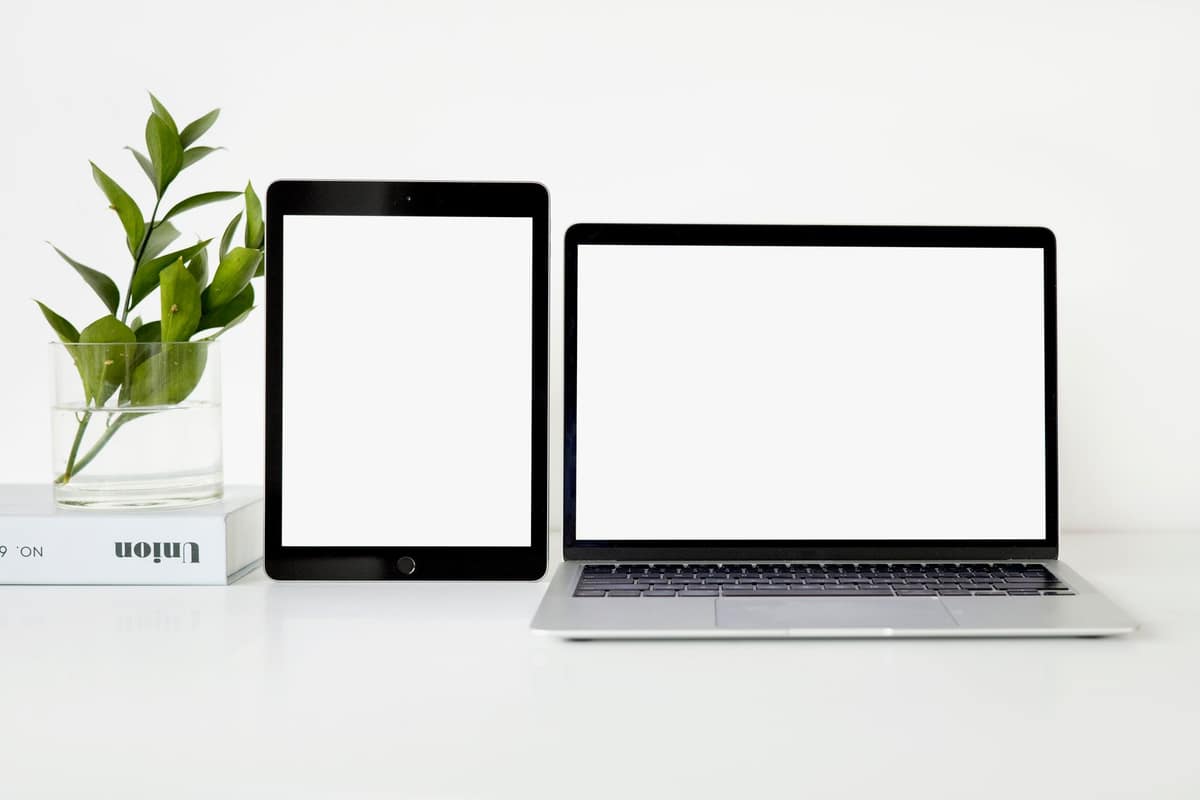 A laptop and tablet on a bright minimal desk