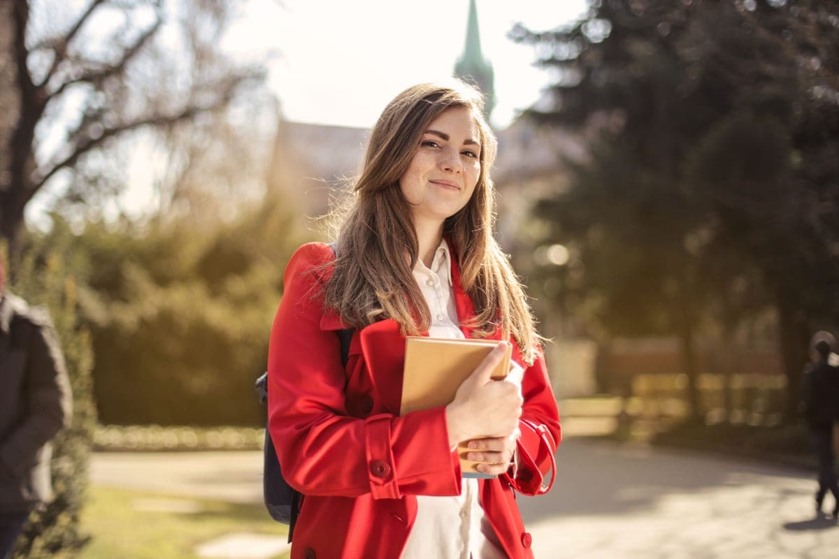 A student smiling on a sunlit university campus