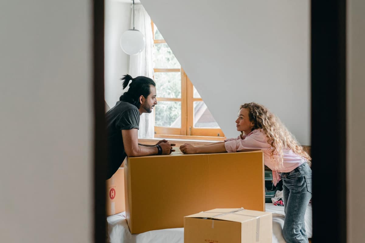 Two students leaning on moving boxes in a bright room