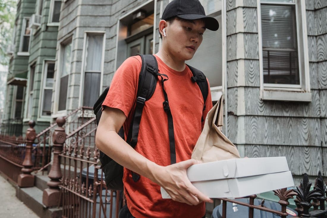 A takeout delivery bag left on a doorstep in bright daylight