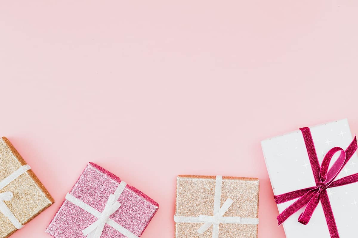 Wrapped gift boxes with pink ribbons on a pale pink background