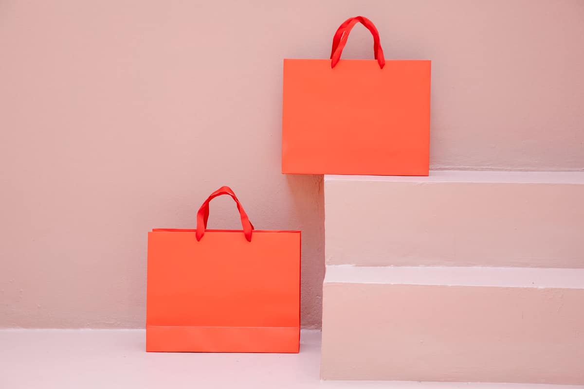 Two orange shopping bags on pale pink steps