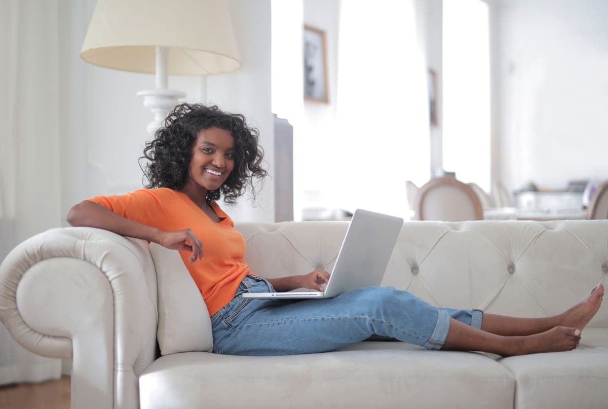 Someone relaxing on a sofa with a laptop in a bright living room