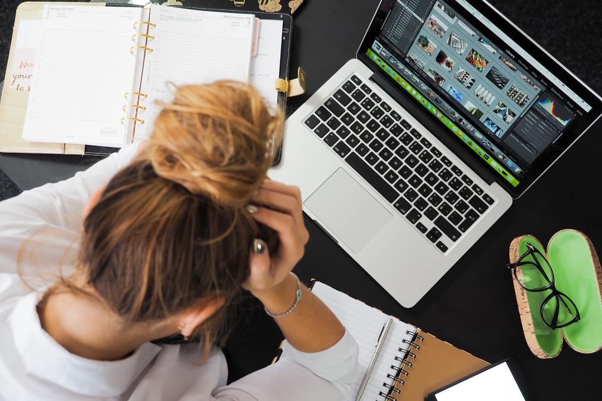 A person looking at a laptop with a puzzled expression at a bright desk