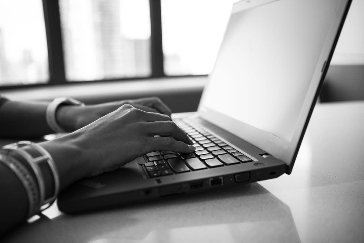 Hands typing on a laptop keyboard at a bright desk
