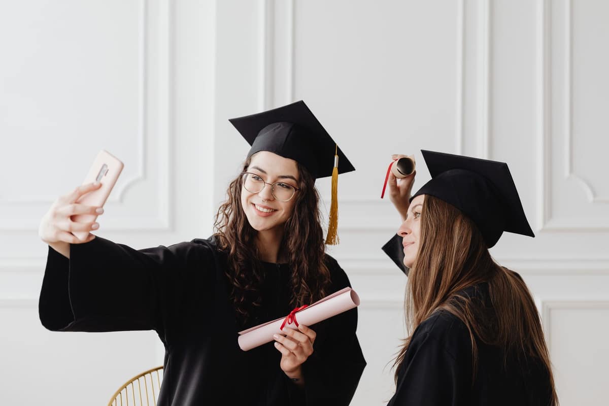 Two graduates in gowns taking a photo together