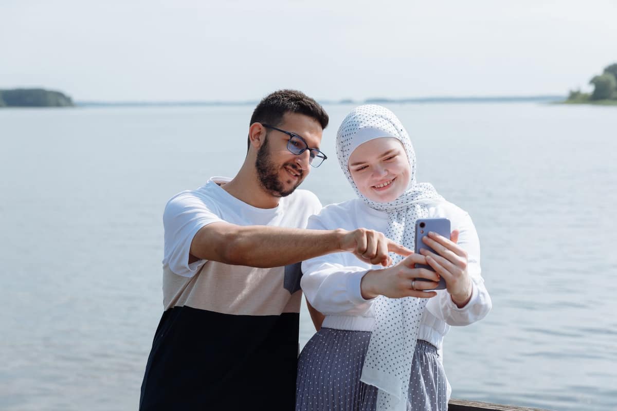 Two young adults looking at a phone together outdoors