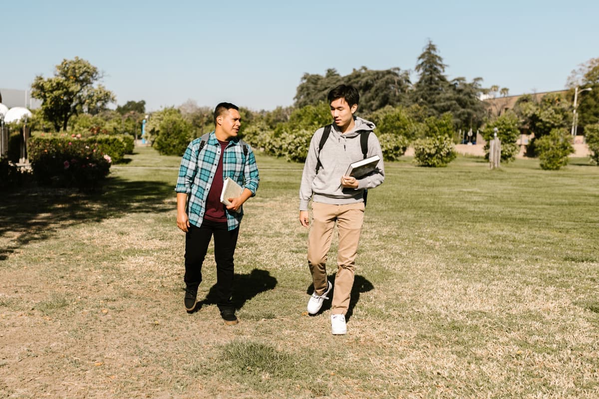 A student walking along a campus path on a sunny day