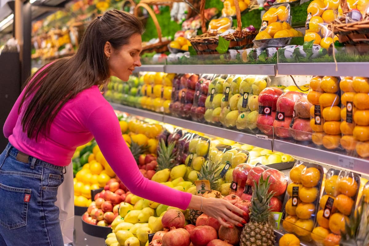 Someone choosing fresh fruit in a grocery store aisle