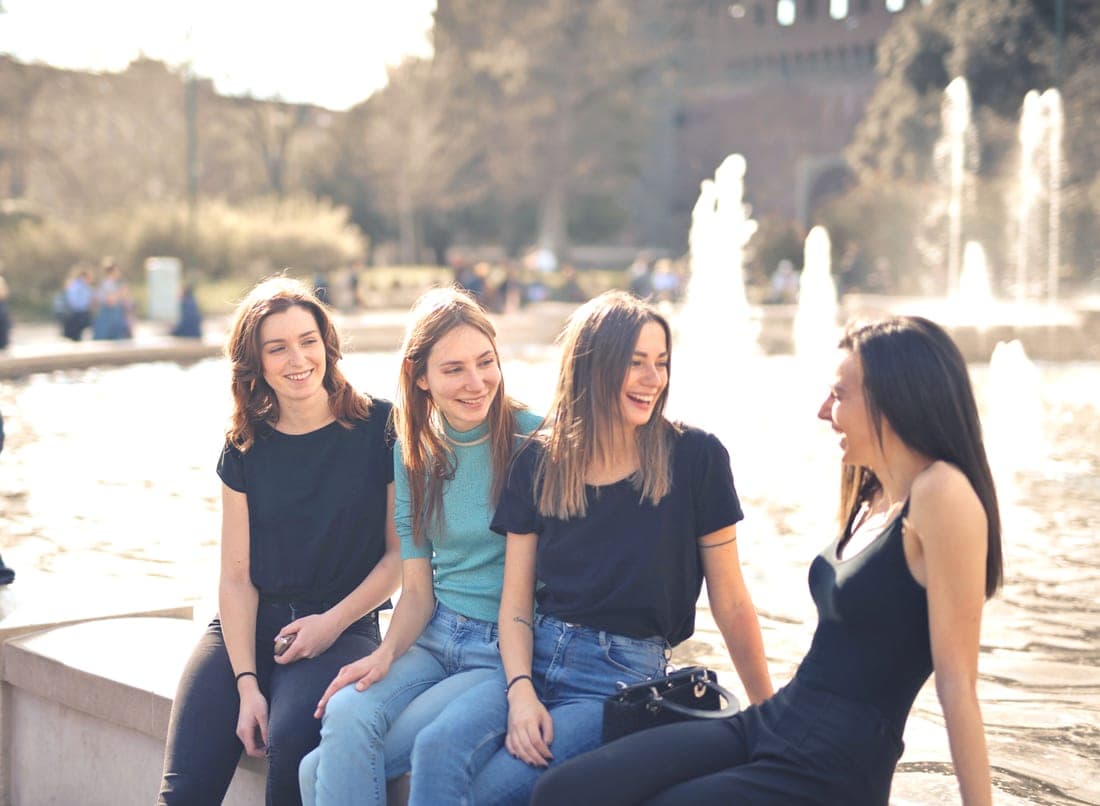 A group of young adults laughing together outdoors on a sunny day